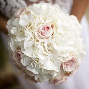 A rounded bouquet combining white hydrangeas and ivory roses